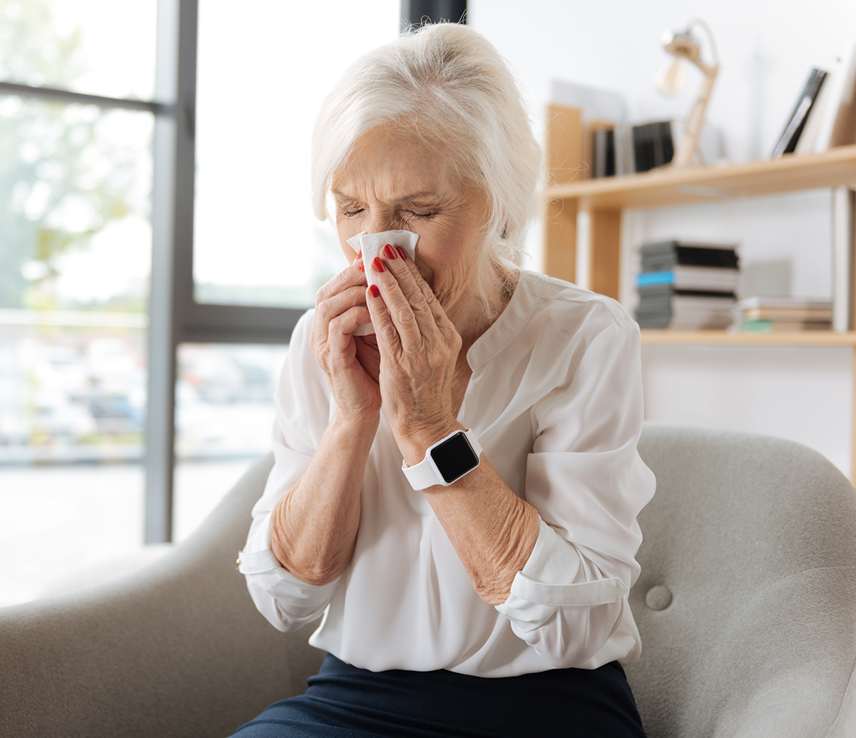 Unhappy elderly woman sneezing