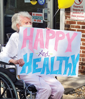 female resident holding a handmade sign that says Happy and Health, during quarantine