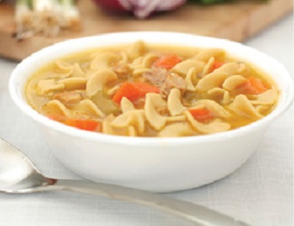 close up photo of a large white ceramic bowl of chicken noodle soup