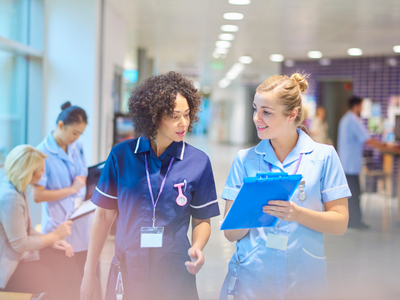 two nurses in scrubs walking in hallway of hospital