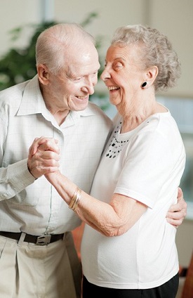 older male and female couple smiling and dancing hand in hand