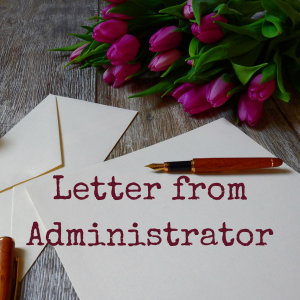 blank paper, brown pen, and envelope on wood table next to bouquet of fuchsia tulips.