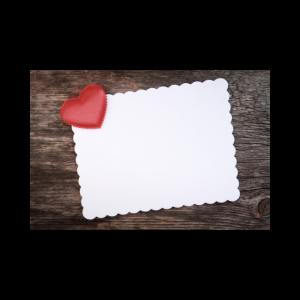 red heart on blank white paper cardboard invitation on a wooden background