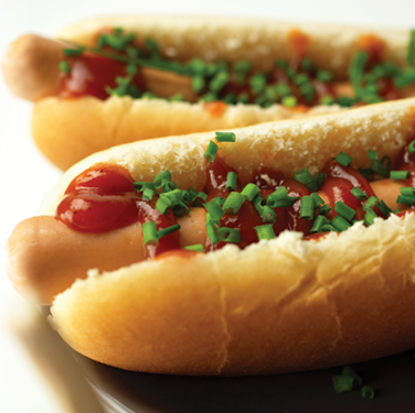 two hotdogs with ketchup and chives